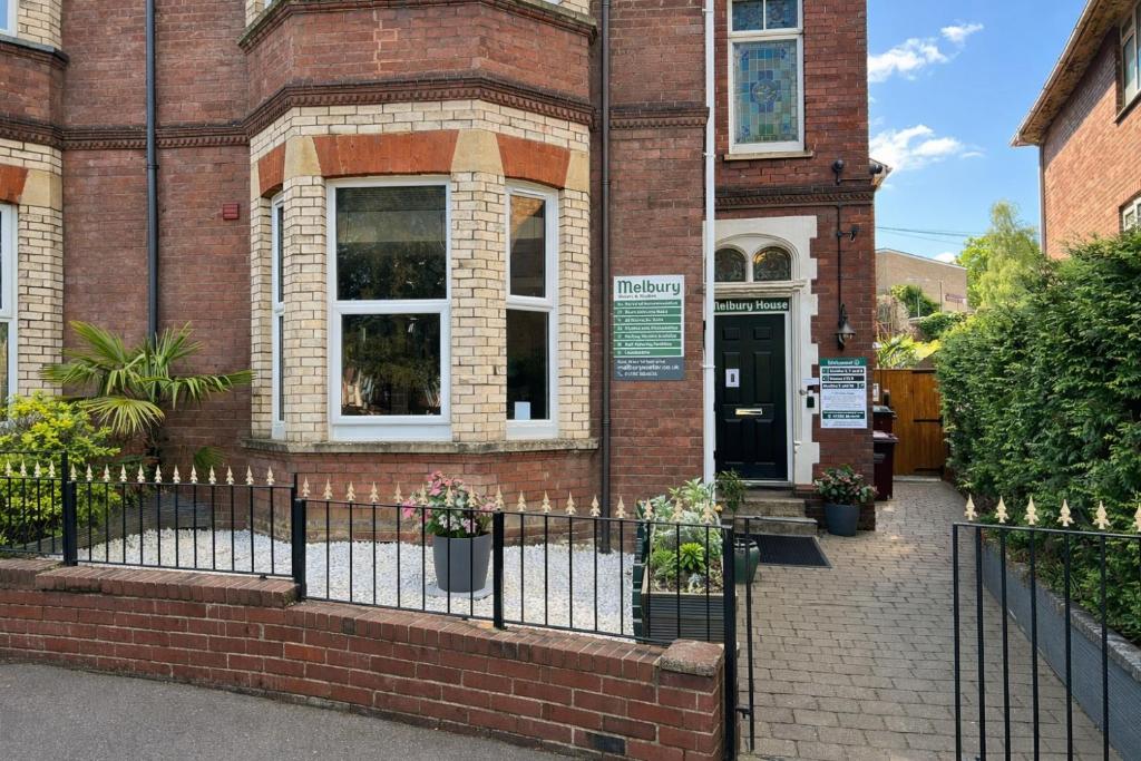 a brick building with a black fence in front of it at Melbury Rooms & Studios in Exeter
