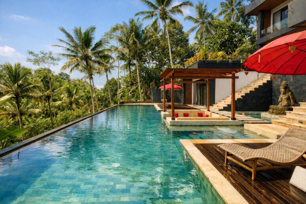 a pool at a resort with a red umbrella at Oran Villa Bali in Tampaksiring