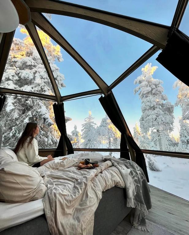 a woman sitting in a bed in a room with a window at Syöte Igloos in Syöte