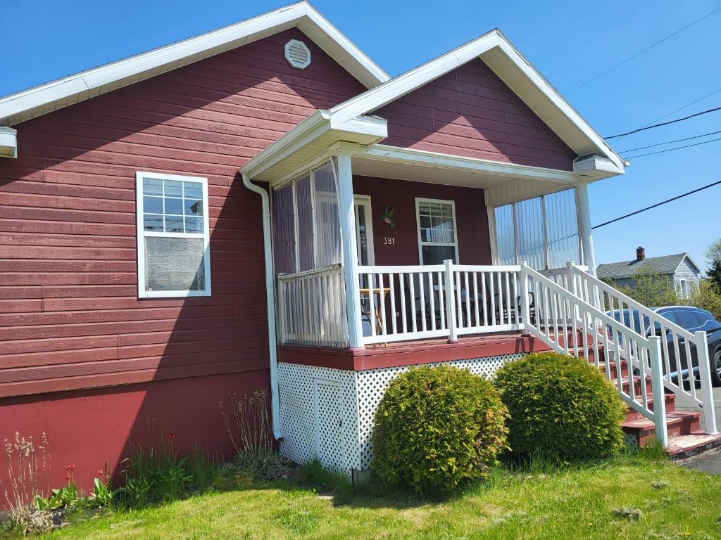 a red house with a porch and a white railing at Nice and cozy in Dalhousie