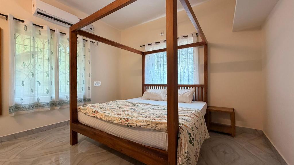 a bedroom with a four poster bed and windows at Athiratha Living in Malpe