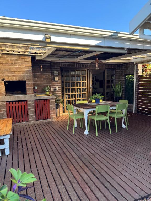 a patio with a table and chairs on a deck at Picasso's Cottage in Gqeberha