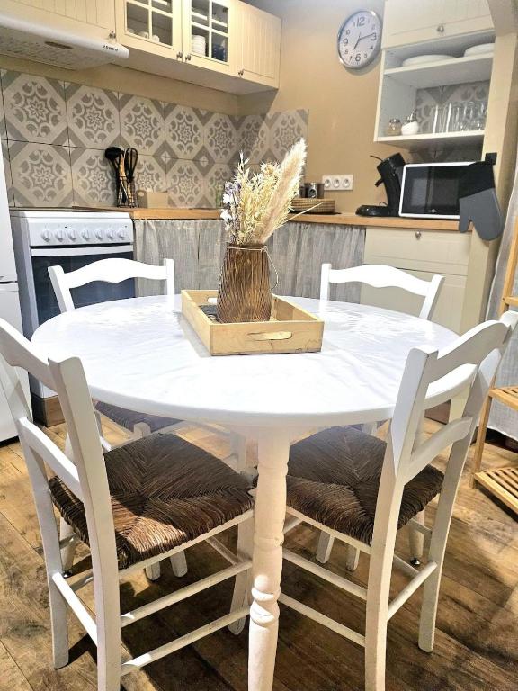 a white table with white chairs and a kitchen at La petite maison dans la bastide in Carcassonne