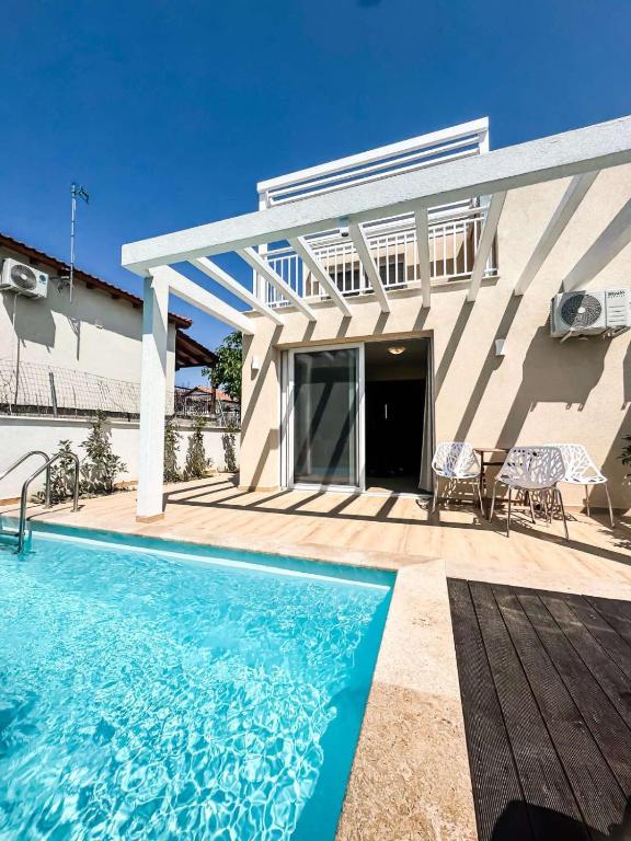 a house with a swimming pool and a patio at Seaside Pool Villas by BookVillaEU in Nea Kallikrateia