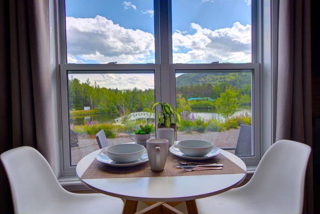 a table and chairs in front of a large window at Lakeside Gateway 4 Spa Sauna Firepit in Sainte Brigitte de Laval