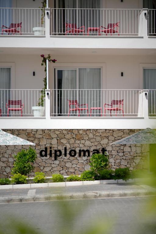 an apartment building with red chairs on a stone wall at Diplomat Suites in Marmaris