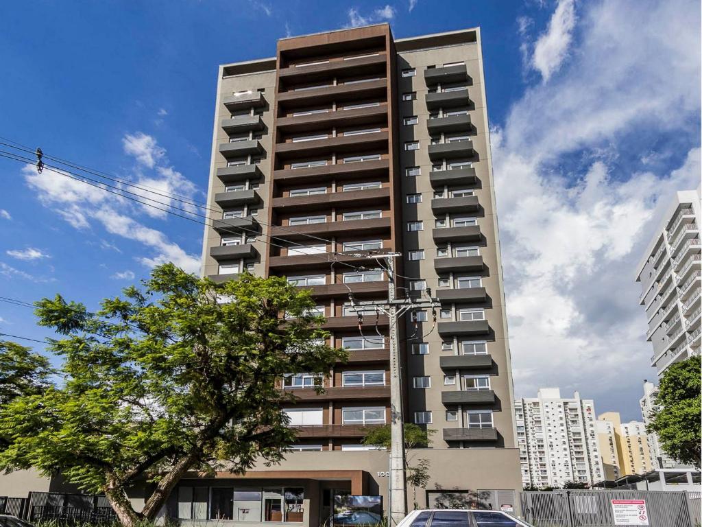 a tall apartment building with a tree in front of it at Connect João Wallig by My Way in Porto Alegre