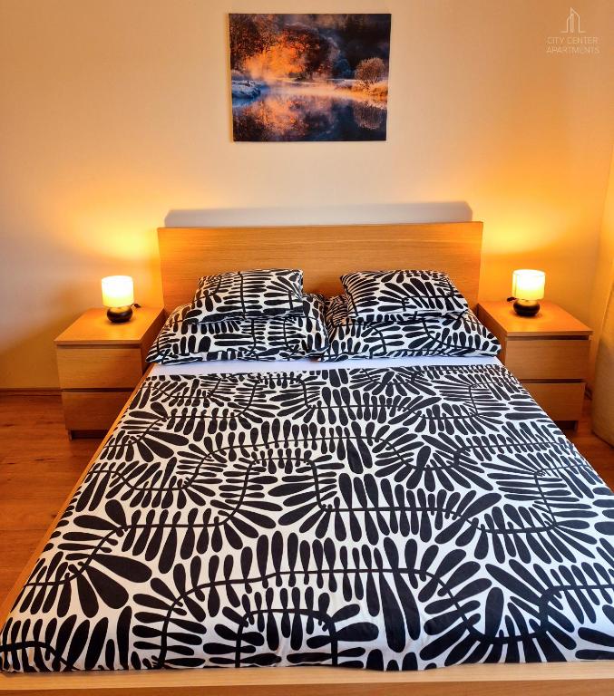 a bedroom with a black and white bed with two lamps at City Center Apartments - Moderna Brno Římské náměstí IV in Brno