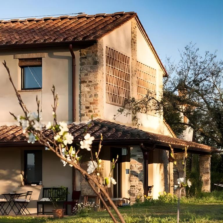 an old stone house with a tree in front of it at Bosco Ai Marzi - 2 Apartments with shared pool in Poggibonsi