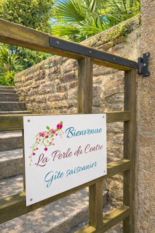 a sign attached to a wooden gate with flowers on it at La perle du Centre à Cancale in Cancale