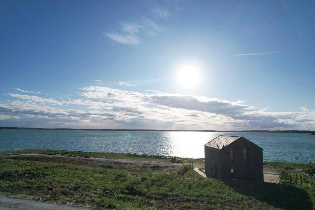 a small building on the shore of a body of water at Ferienhaus Sonnenwasser am Partwitzer See in Klein Partwitz