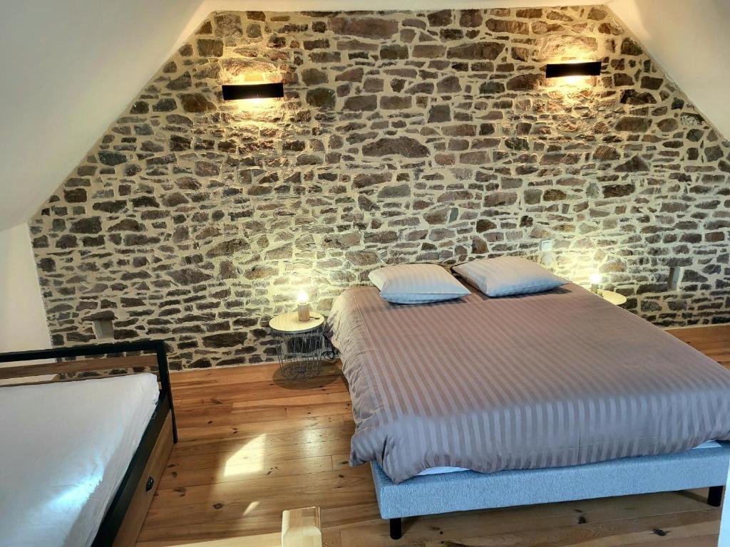 a bedroom with a bed and a stone wall at Petit Loft, Maison Bord De Mer in Pirou