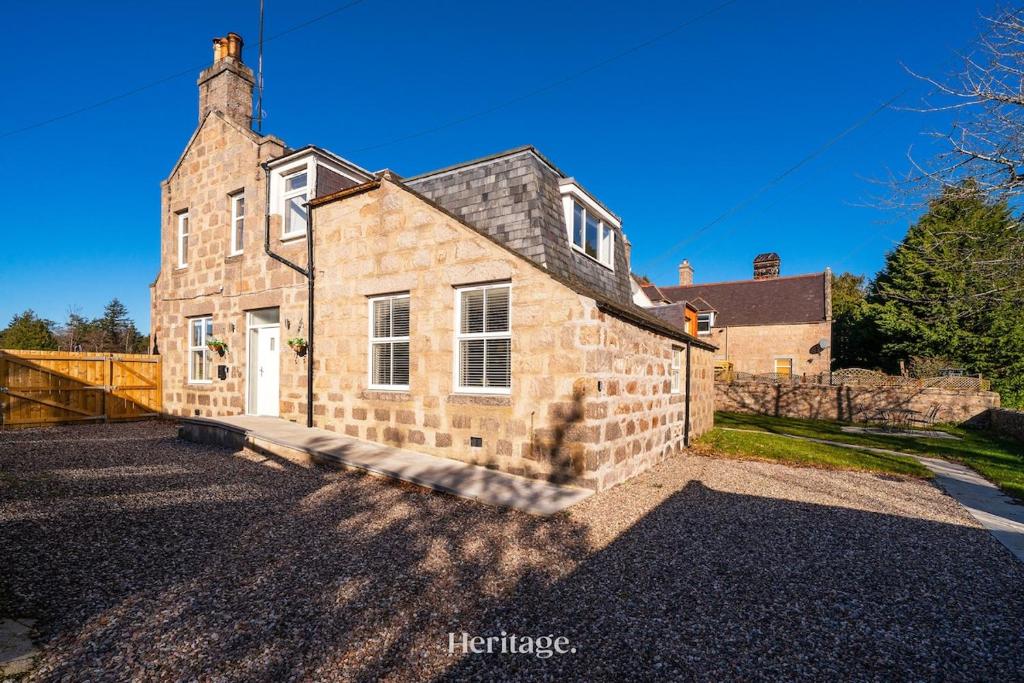 an old stone house with a brick wall at The Old Sorting Office, Aboyne, Royal Deeside in Aberdeen