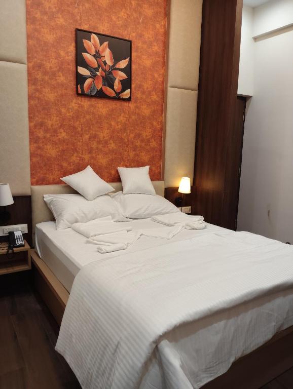 a bedroom with a large white bed with an orange wall at Gamagashree Hotel and Fine Dine in Sāgar