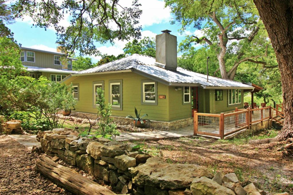 a small green house with a stone wall at Frog Cottage on the Blanco in Wimberley