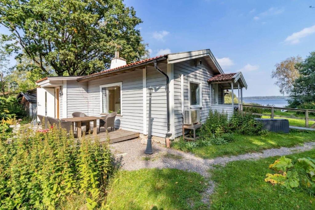a small white cottage with a wooden porch and a table at VGO922-Grabo-Strandkullen-22 in Gråbo