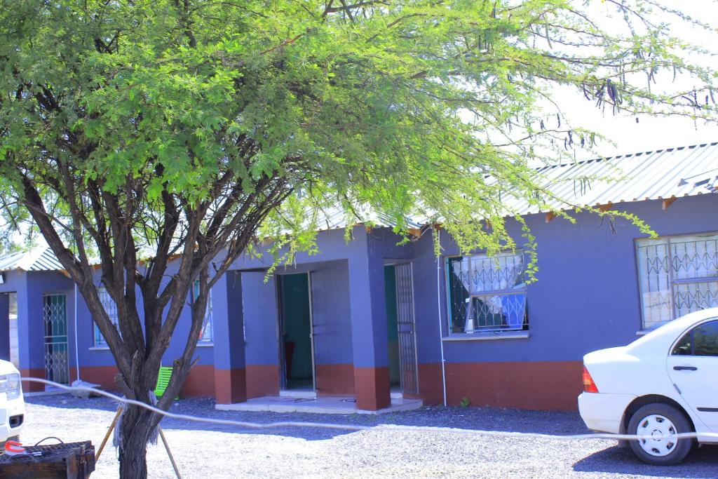 a blue and red building with a tree in front at Equatorial Guest House in Rustenburg