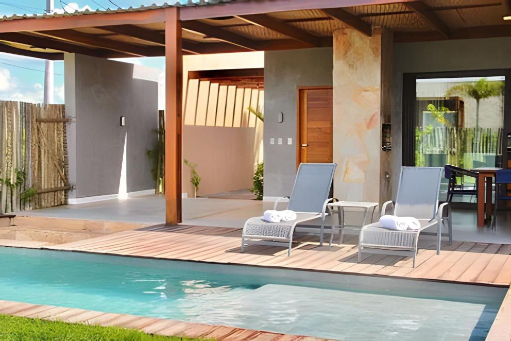 a patio with two chairs and a swimming pool at Condominio Uhane Luxury Villas in São Miguel do Gostoso