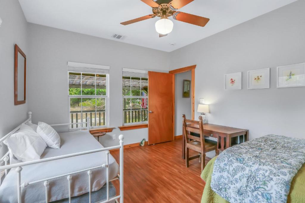 a bedroom with a bed and a desk and a ceiling fan at Fairlawn on the Blanco in Wimberley
