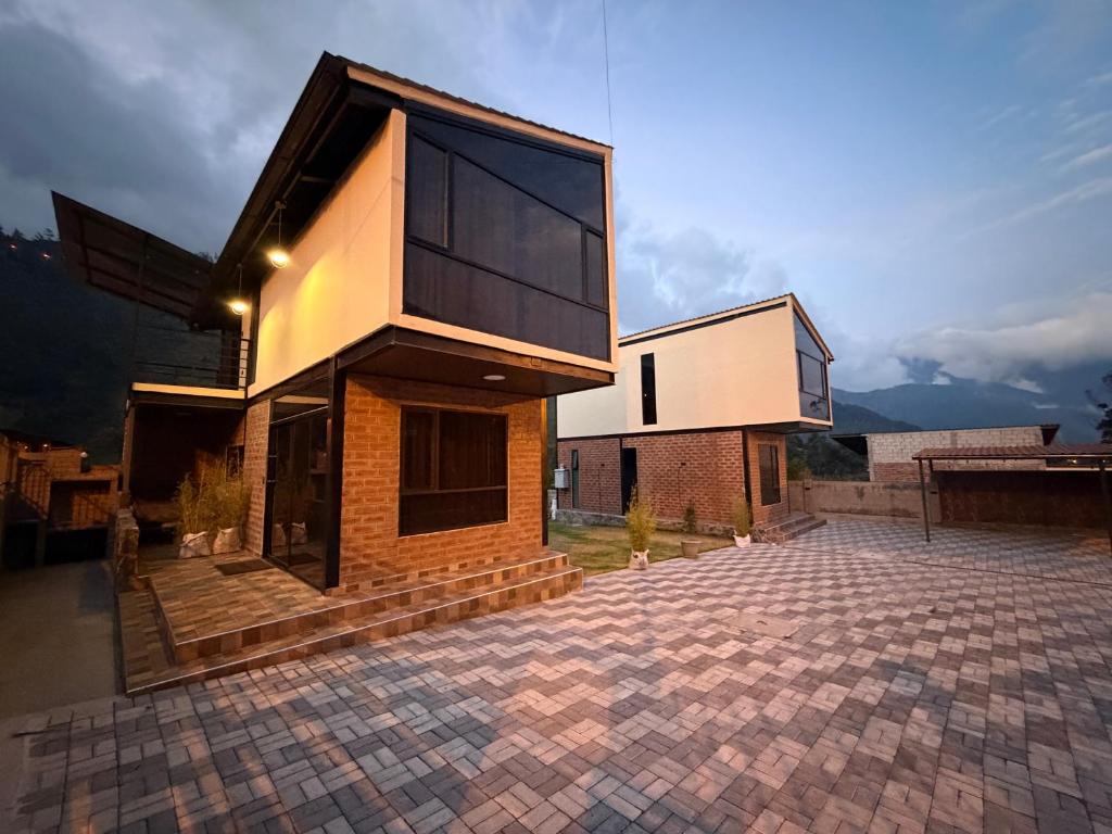 a house with a large window on a brick driveway at Relajate en una TinyHouse privada en Baños de Agua Santa con Jacuzzi y vistas increíbles in Baños