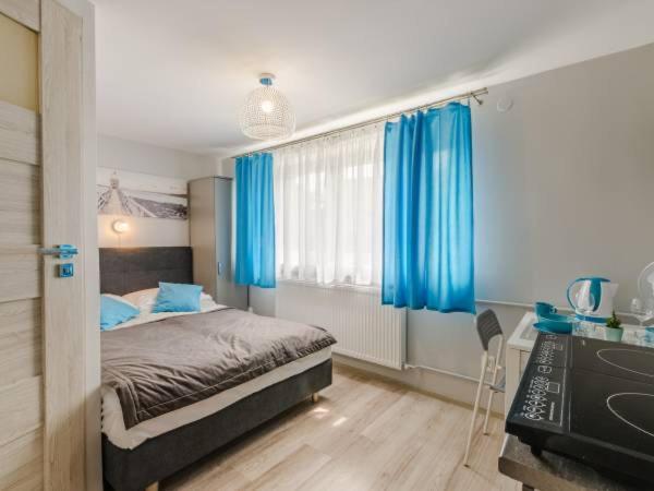 a bedroom with blue curtains and a bed and a desk at Spełniony sen in Stegna
