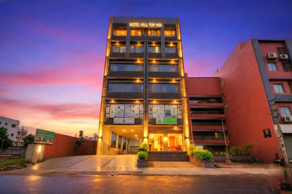 a tall building with a sunset in the background at hotel hill top inn vatva in Ahmedabad