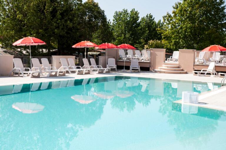 a large swimming pool with chairs and umbrellas at VILLAGGIO TURISTICO LA FOCE SpA in Toscolano Maderno