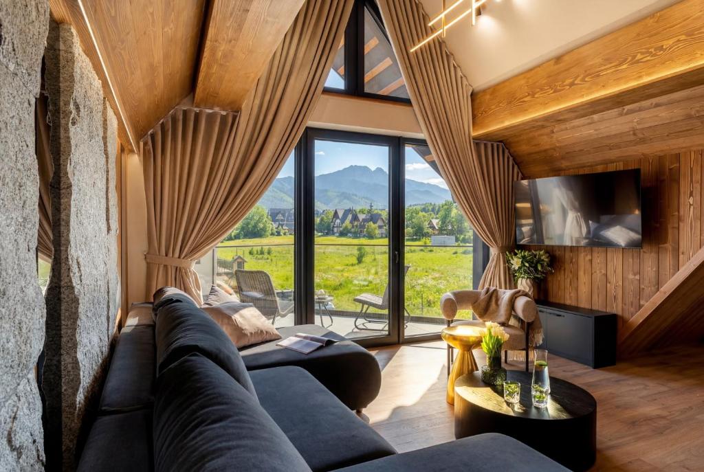 a living room with a couch and a large window at CHATAR Tatra Premium Suites in Zakopane