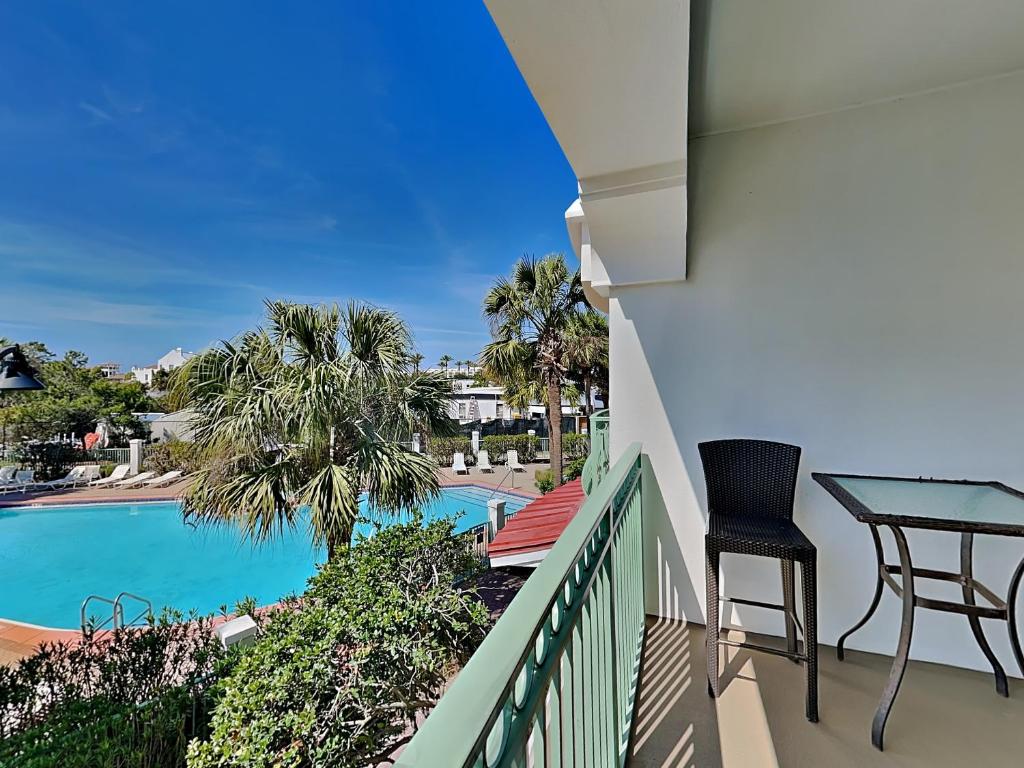 a balcony with a table and chairs next to a swimming pool at Inn at Seacrest #206 in Rosemary Beach