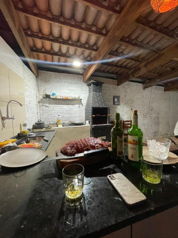 a kitchen with a counter with bottles of wine and meat at Casaacochego in Icapuí