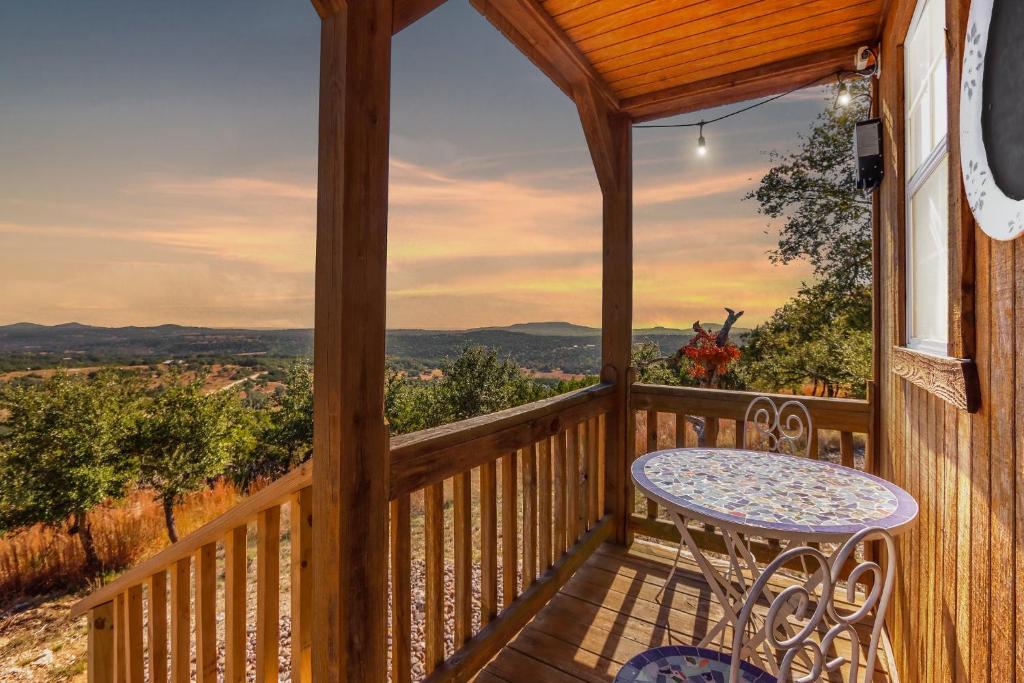 a wooden porch with a table and a view of the mountains at Daybreak Ridge Sunrise Bluff in Blanco