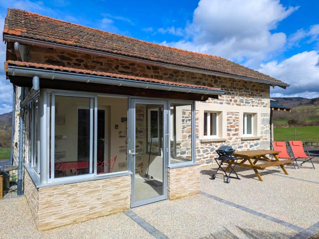 a small cottage with a picnic table and a grill at Le gîte d'Ouillon in Saint-Hostien