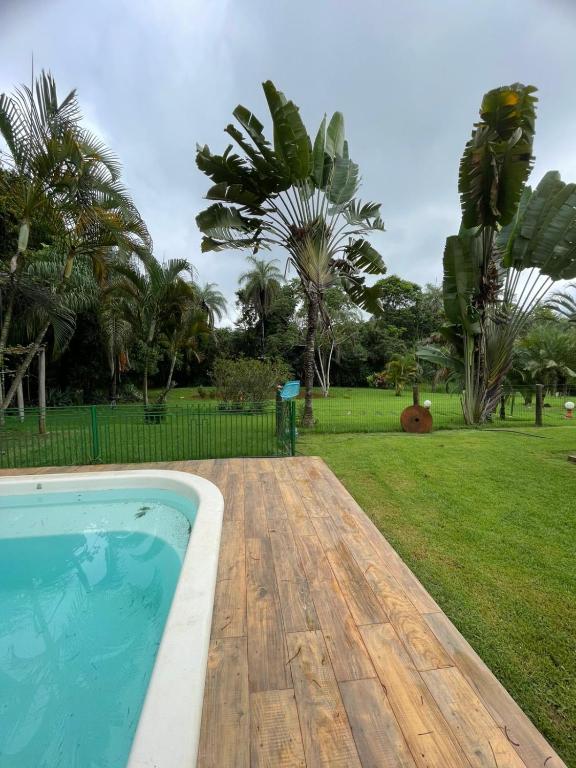 a swimming pool with a wooden deck next to a park at Sítio Funilândia - MG in Funilândia