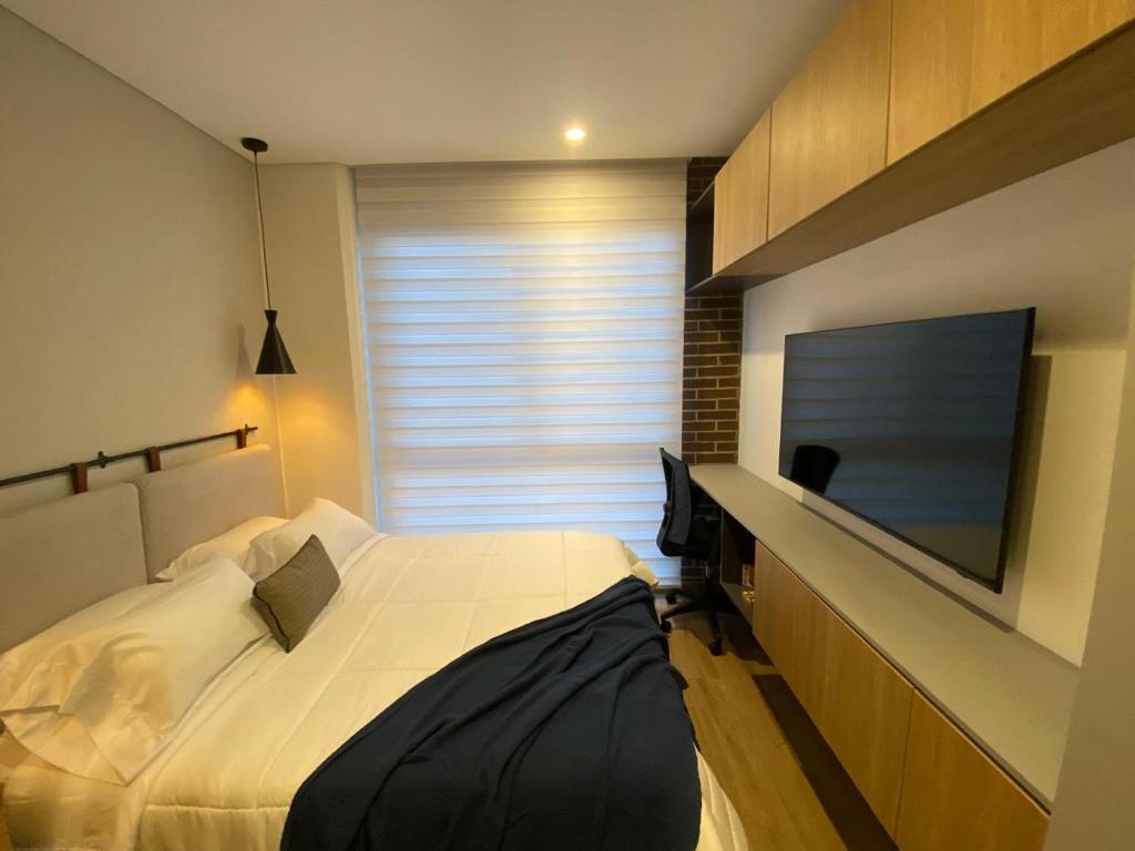a bedroom with a bed and a flat screen tv at Apartasuite Cowork in Bogotá