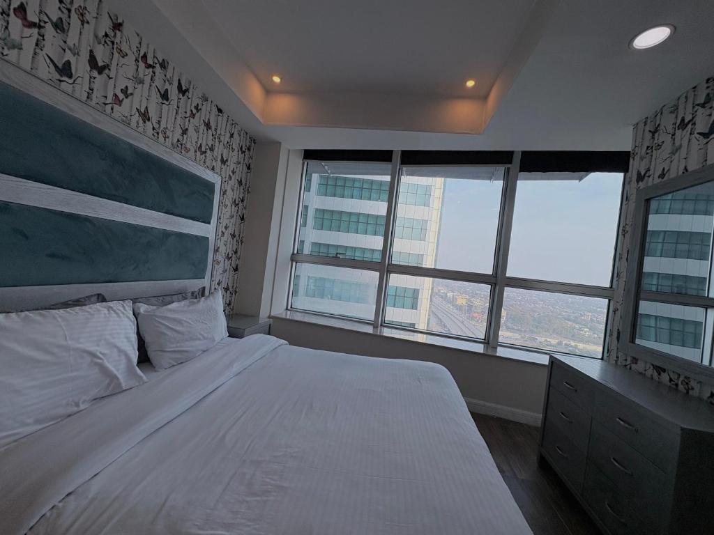 a bedroom with a large bed and two windows at MZK Apartment in Islamabad