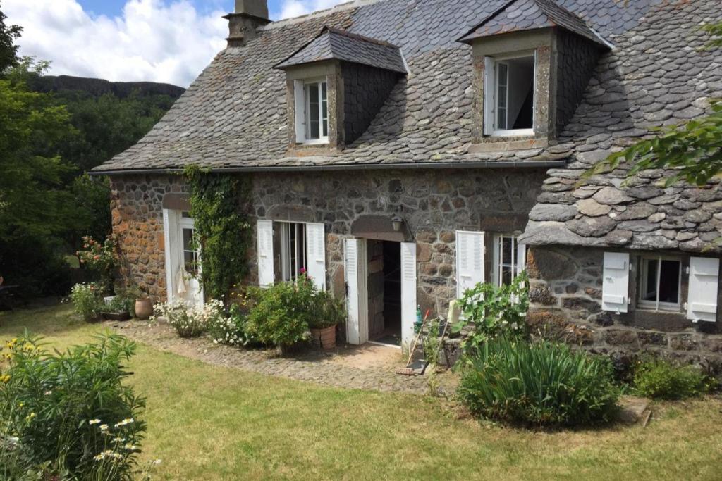 an old stone house with a grass yard at Gite de collandres in Cheylade