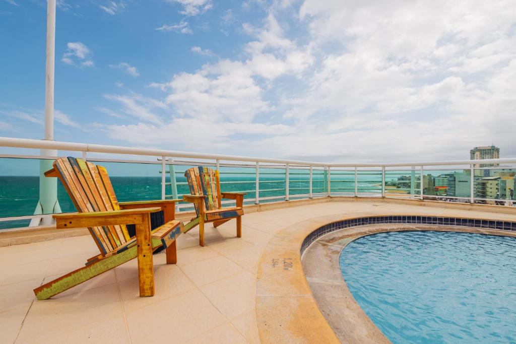 a balcony with two chairs and a swimming pool on a cruise ship at Ibis Styles Macaé in Macaé
