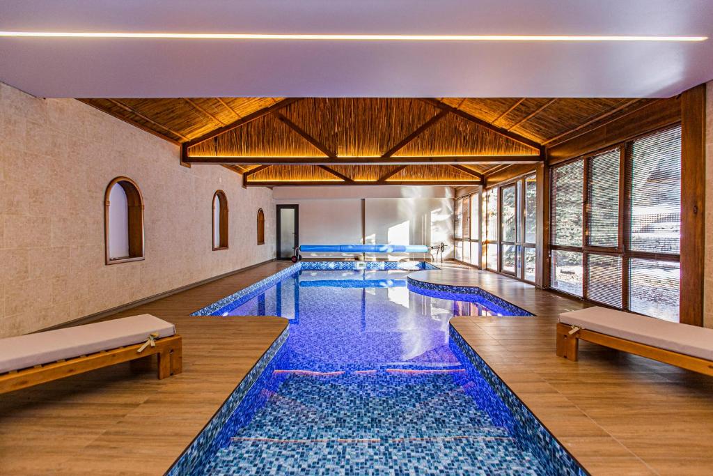a pool with blue tiles in a building with windows at Ermensai Wellness Boutique Hotel in Almaty