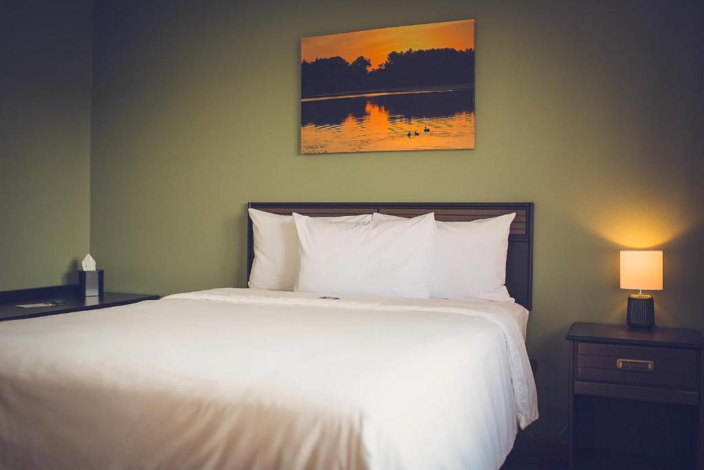 a bedroom with a white bed and a painting on the wall at Forrest Inn in Amery
