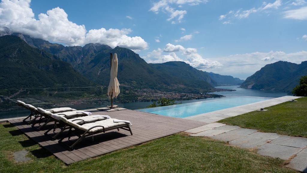a deck with chairs and an umbrella and a river at Villa Valentina by Rent All Como in Civenna