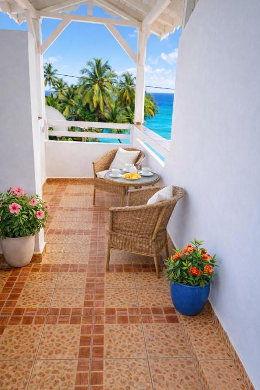 a balcony with a table and chairs and the ocean at Appartement 5 pers proche plage Capesterre in Capesterre-Belle-Eau
