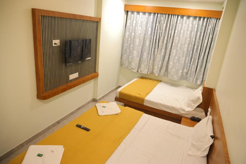 a small room with a bed and a window at Hotel Sumeet Palace in Shirdi