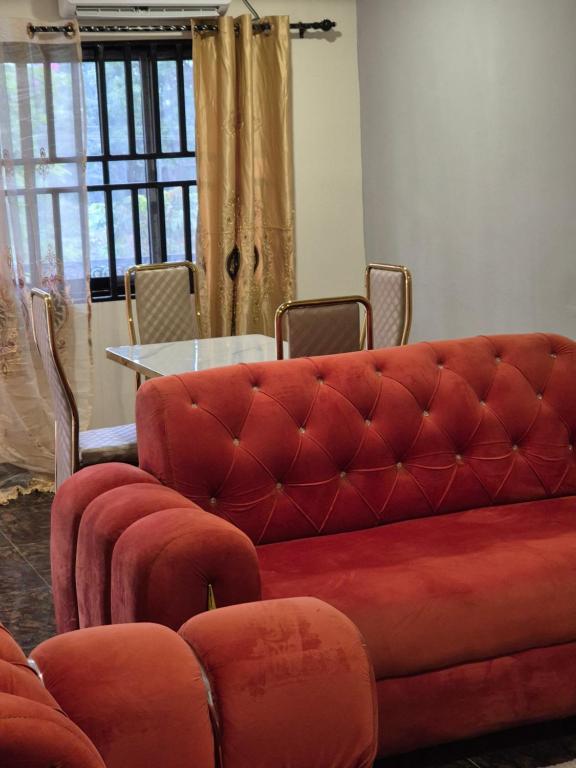 a living room with a red couch and a table at G and E Guesthouse in Kumba