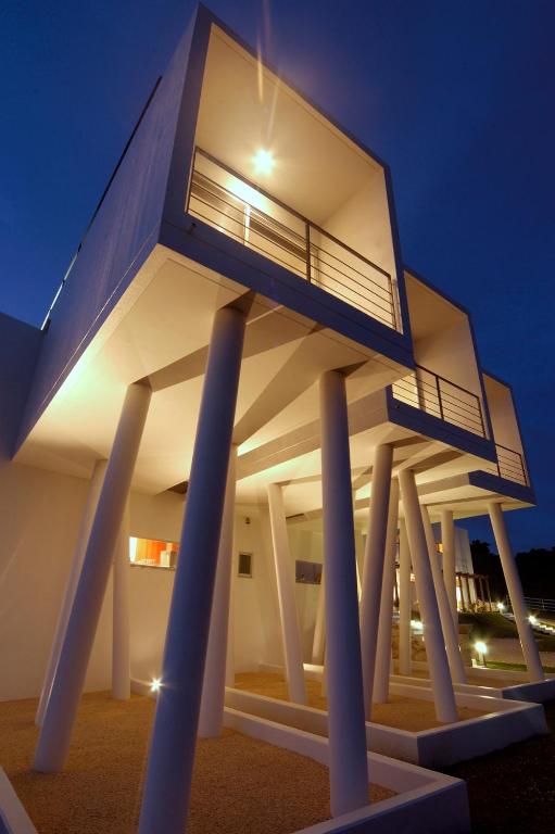 a house on pillars with lights on it at night at Private Resort Hotel RENN in Miyako-jima