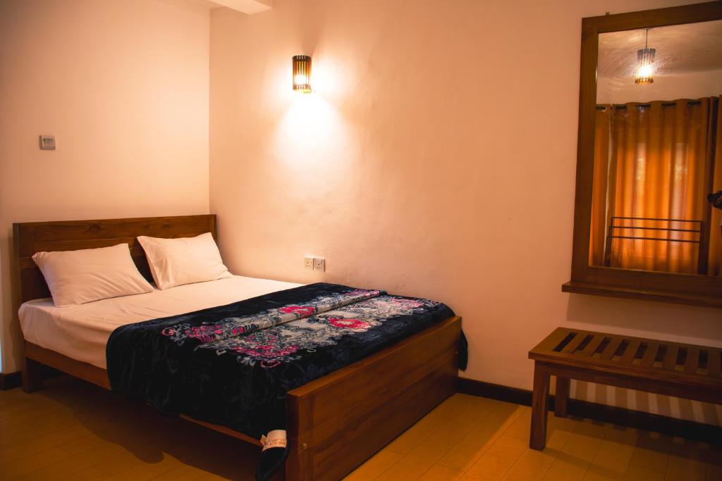 a bedroom with a bed and a mirror on the wall at MGM Daisy Resorts in Nuwara Eliya