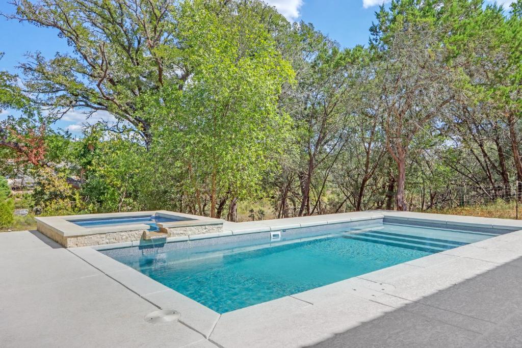 a swimming pool in a yard with trees in the background at Barndo on the Blanco in Wimberley