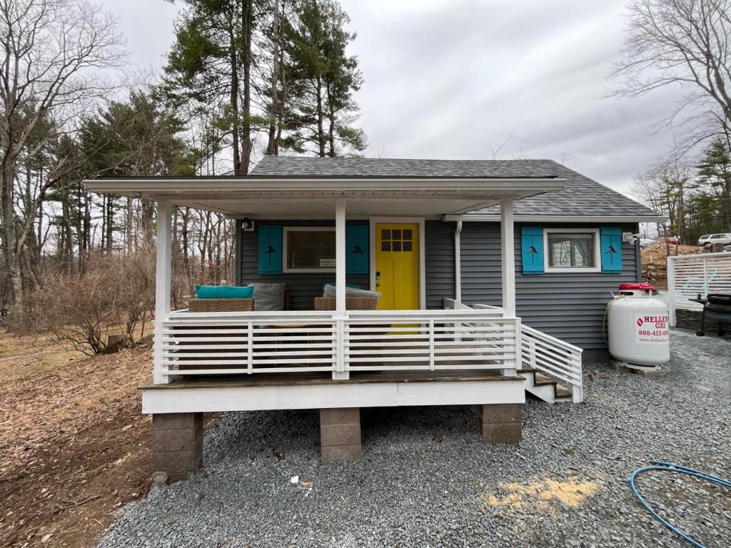 a tiny house with a porch and a yellow door at Wally’s Matchbox |New|Hot Tub|Fire Pit|Close 2 All in Hawley