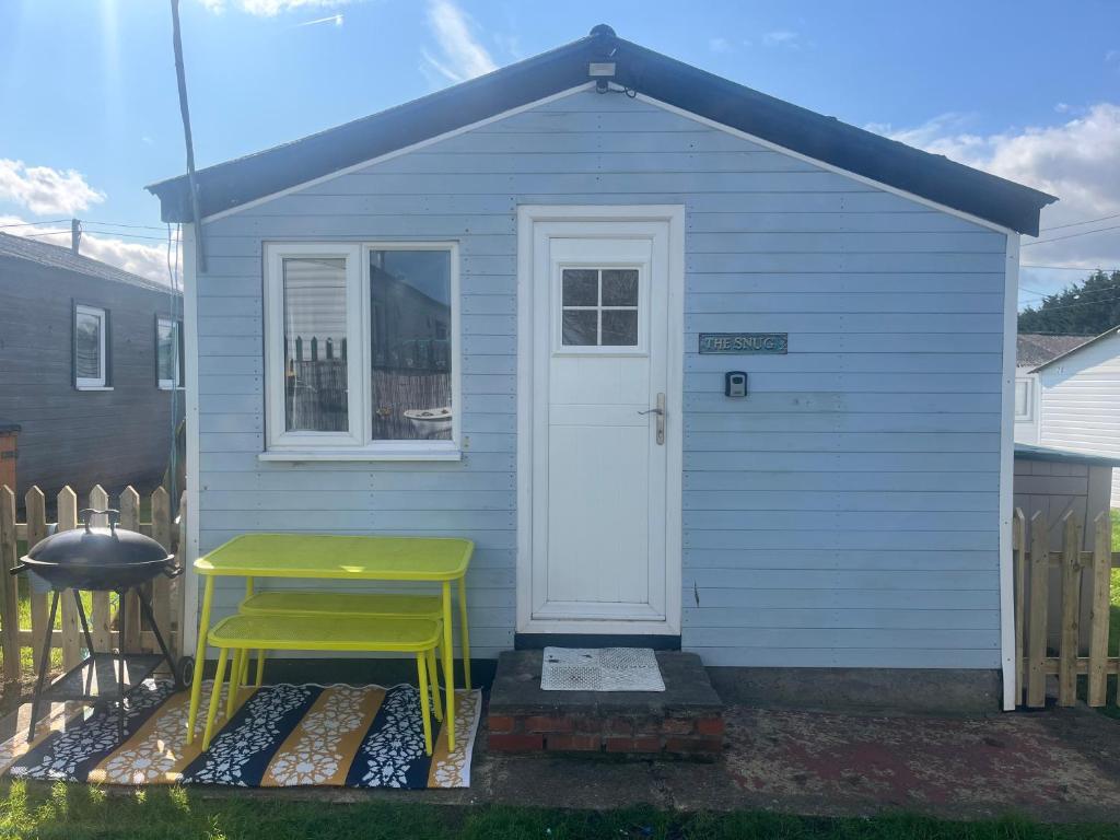 a small blue house with a yellow stool in front of it at The Snug - All Seasons Chalet Breaks in Leysdown-on-Sea