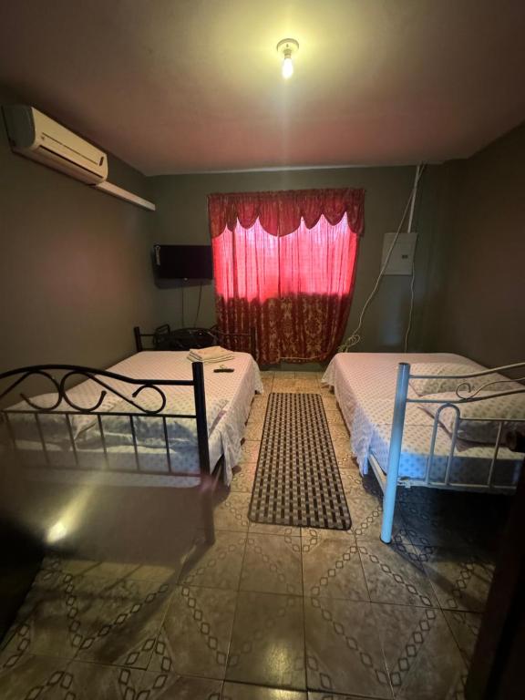 two beds in a room with a red window at Triple K Complex in Kelly Village