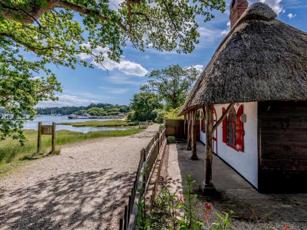 a building with a thatched roof next to a beach at 1 Bed in Brockenhurst oc-78767 in Beaulieu